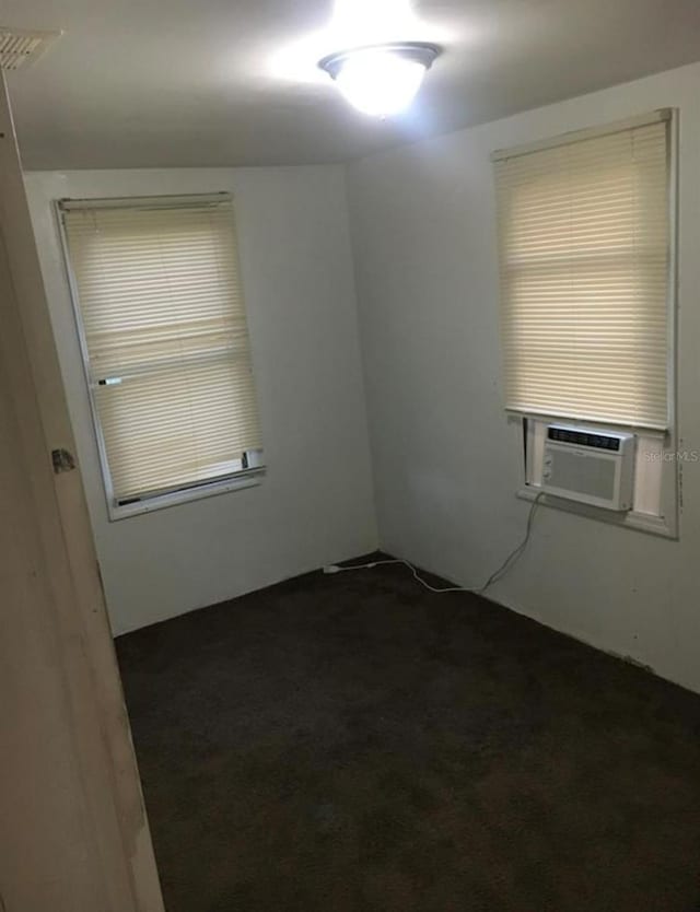 empty room with cooling unit and dark colored carpet