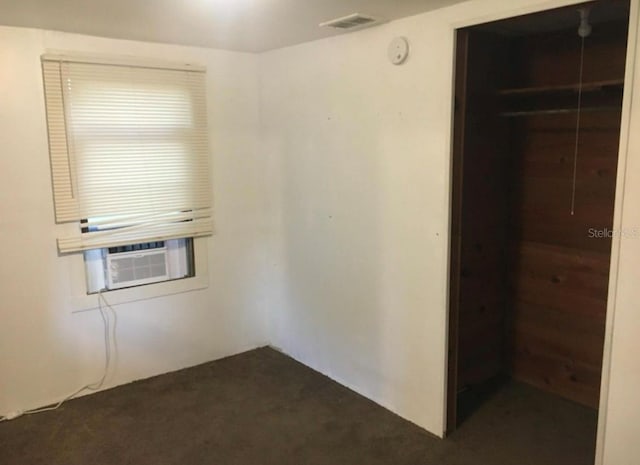 spare room featuring cooling unit and dark carpet