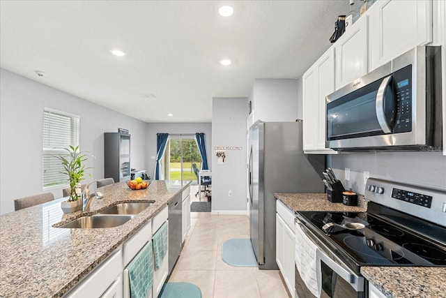 kitchen featuring light tile patterned floors, white cabinets, stainless steel appliances, a sink, and recessed lighting