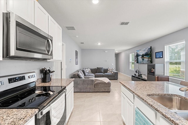 kitchen with visible vents, appliances with stainless steel finishes, white cabinetry, a sink, and light tile patterned flooring