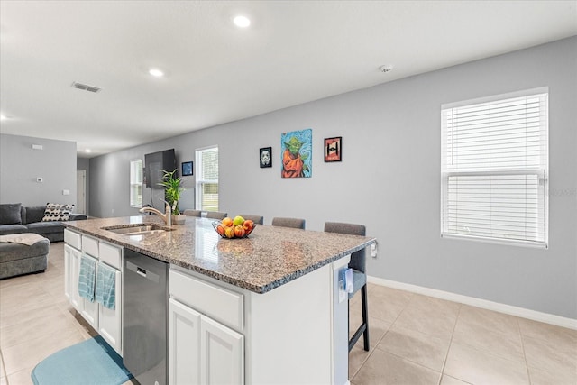 kitchen with light stone counters, visible vents, open floor plan, a sink, and dishwasher