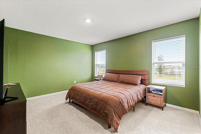 bedroom featuring light colored carpet, multiple windows, a textured ceiling, and baseboards