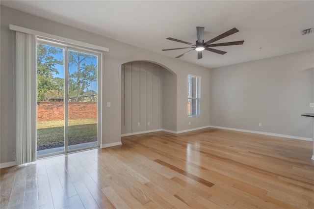 empty room with a healthy amount of sunlight, ceiling fan, and light hardwood / wood-style flooring