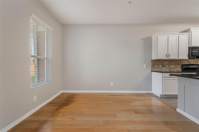 kitchen featuring tasteful backsplash, stove, light wood-type flooring, and white cabinets