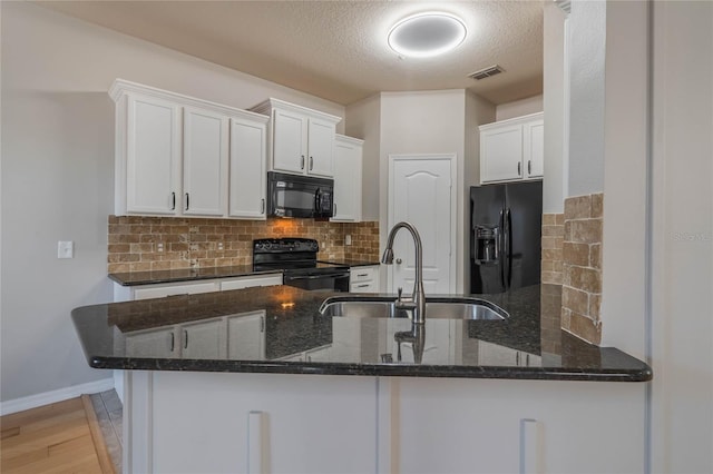 kitchen with white cabinets, dark stone countertops, kitchen peninsula, and black appliances