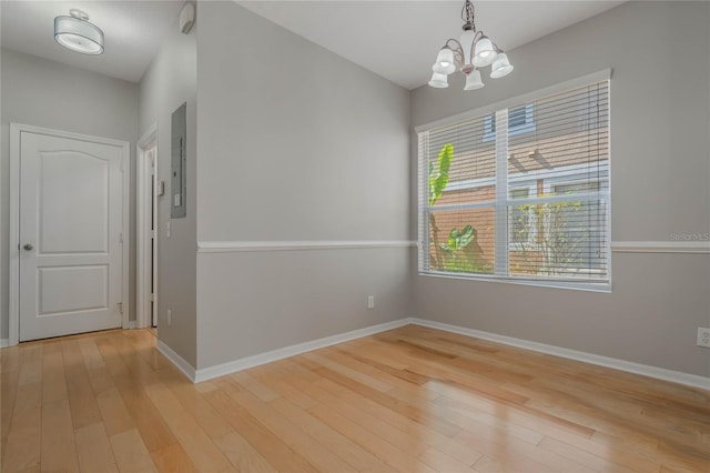 unfurnished dining area with electric panel, a chandelier, and light wood-type flooring