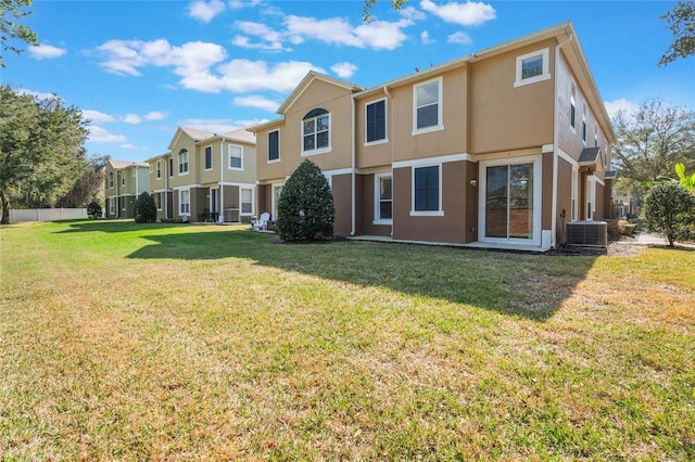 rear view of property with central AC and a lawn