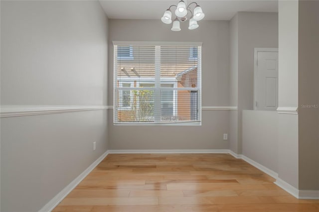 spare room featuring wood-type flooring and a chandelier