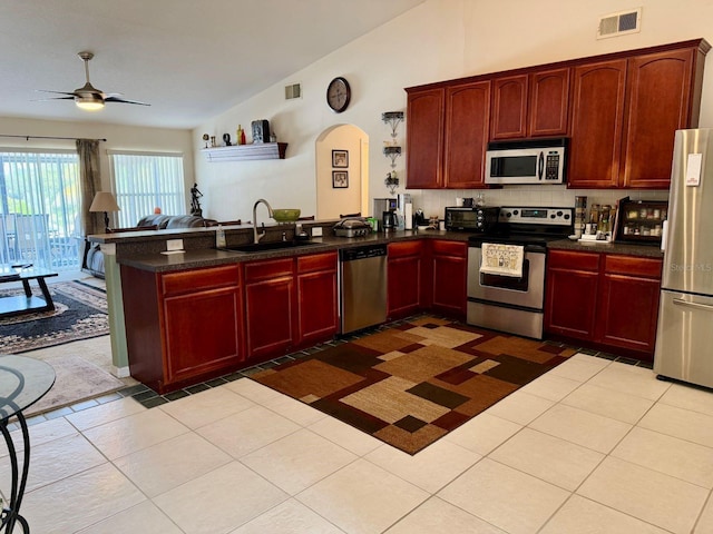 kitchen with sink, stainless steel appliances, light tile patterned flooring, vaulted ceiling, and kitchen peninsula