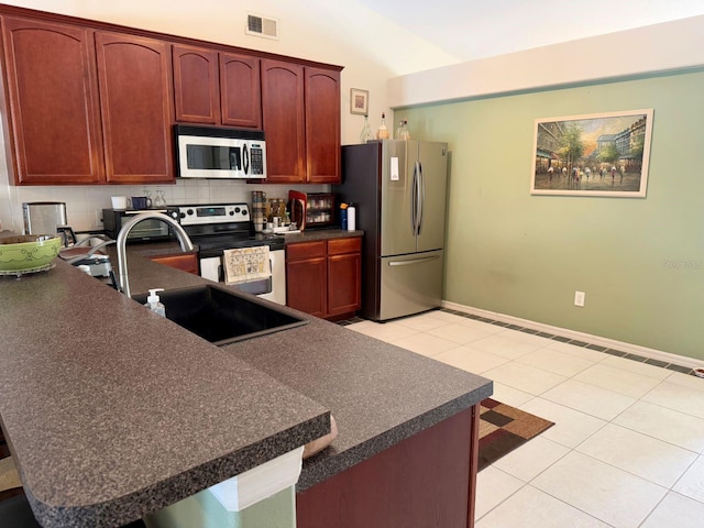 kitchen featuring vaulted ceiling, appliances with stainless steel finishes, light tile patterned flooring, and kitchen peninsula