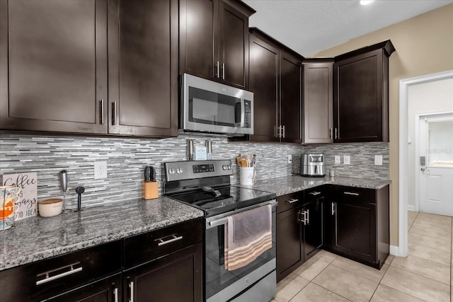 kitchen with appliances with stainless steel finishes, stone countertops, decorative backsplash, light tile patterned floors, and dark brown cabinetry