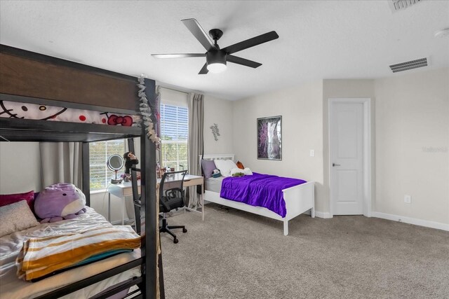 carpeted bedroom featuring ceiling fan and a textured ceiling