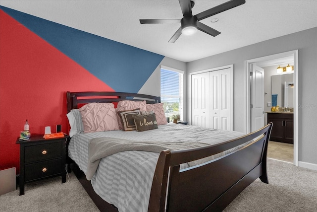 carpeted bedroom with a closet, ceiling fan, and ensuite bathroom