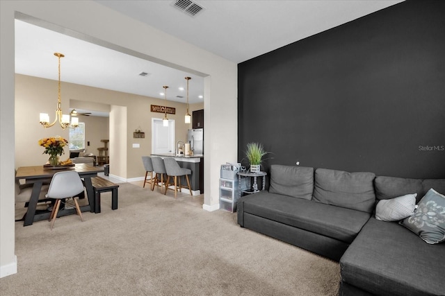 carpeted living room featuring a chandelier