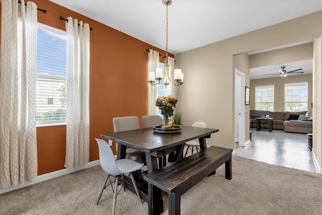 carpeted dining room with plenty of natural light and ceiling fan with notable chandelier