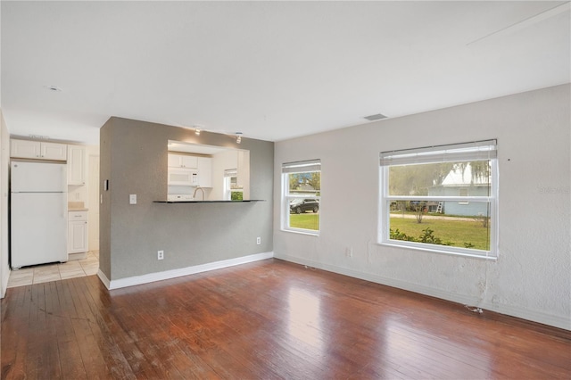 unfurnished living room with baseboards, wood-type flooring, and visible vents