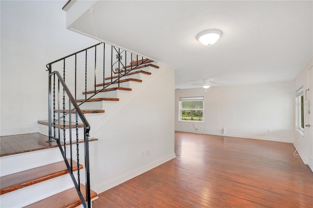 stairs with baseboards, wood finished floors, and a ceiling fan