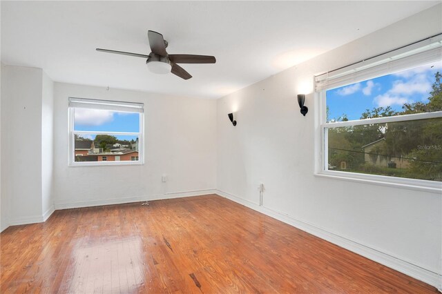 spare room featuring baseboards, wood-type flooring, and a ceiling fan