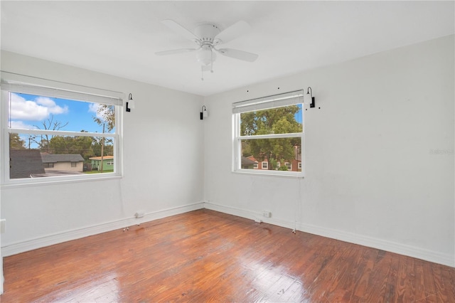 spare room with baseboards, plenty of natural light, ceiling fan, and hardwood / wood-style flooring