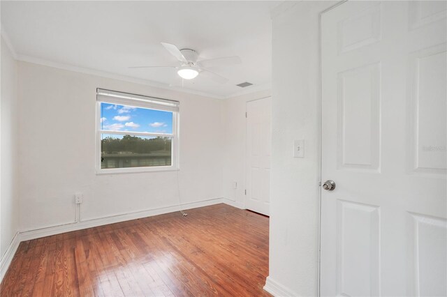 unfurnished room featuring visible vents, ornamental molding, wood finished floors, baseboards, and ceiling fan