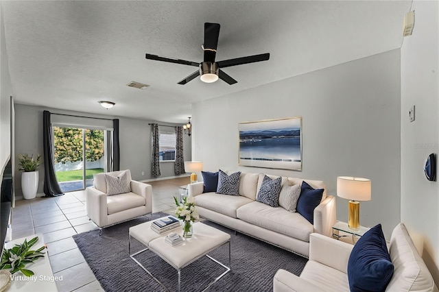 living room featuring ceiling fan, a textured ceiling, and light tile patterned flooring