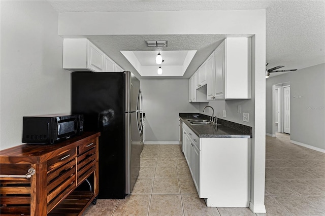 kitchen with sink, stainless steel refrigerator, white cabinetry, a tray ceiling, and a textured ceiling