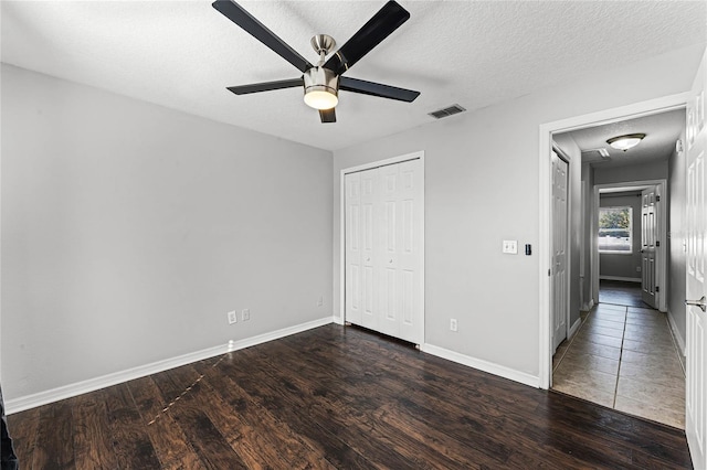 unfurnished bedroom featuring ceiling fan, dark wood-type flooring, a closet, and a textured ceiling