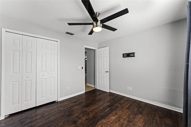 unfurnished bedroom featuring ceiling fan, dark hardwood / wood-style floors, a closet, and a textured ceiling