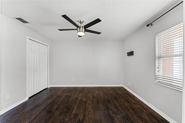 unfurnished bedroom featuring dark wood-type flooring, ceiling fan, a closet, and a textured ceiling