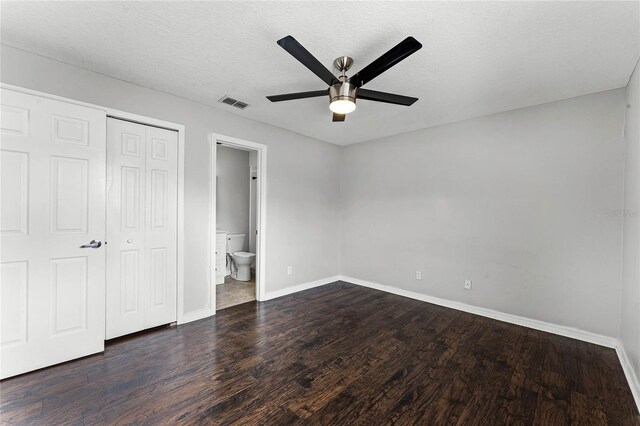 unfurnished bedroom featuring connected bathroom, ceiling fan, dark wood-type flooring, a textured ceiling, and a closet