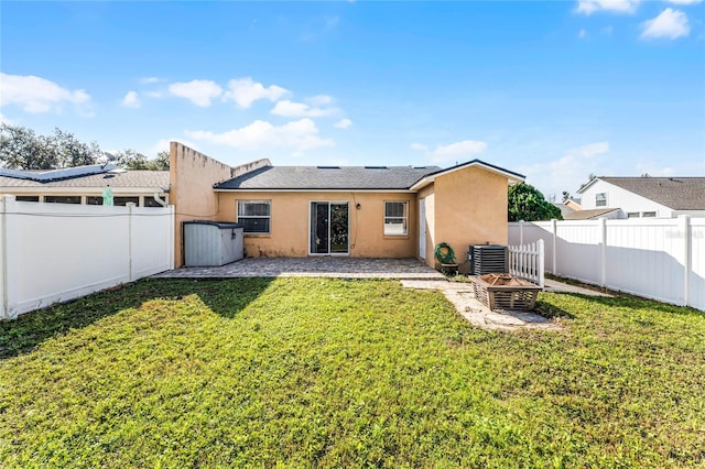 rear view of house featuring a lawn, central AC unit, and a fire pit