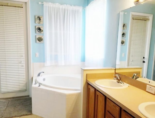 bathroom featuring vanity, a relaxing tiled tub, and tile patterned floors