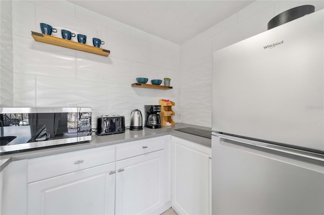 bar with tasteful backsplash, white fridge, and white cabinets