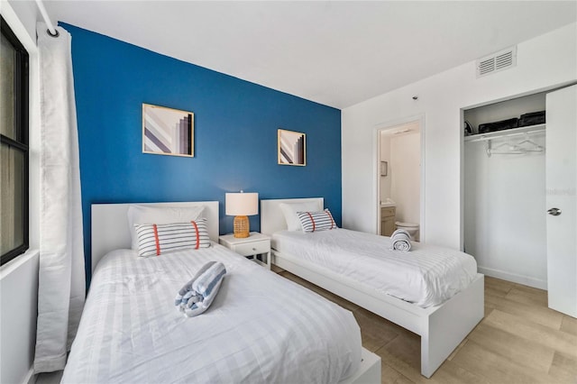 bedroom featuring ensuite bath, a closet, and light wood-type flooring