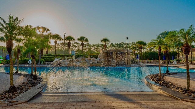 pool at dusk featuring pool water feature