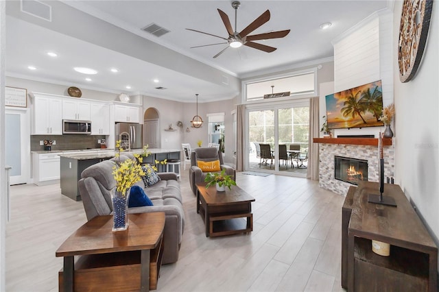 living room featuring crown molding, ceiling fan, and light wood-type flooring