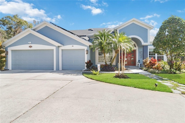 ranch-style home with a garage, a front yard, and solar panels