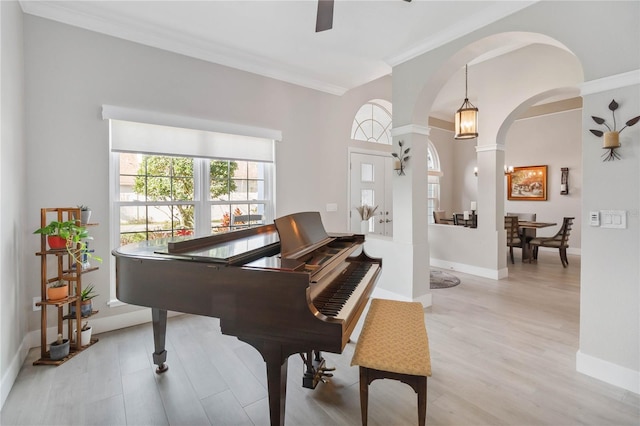 misc room with decorative columns, ornamental molding, light hardwood / wood-style floors, and ceiling fan