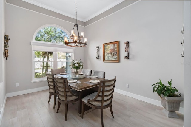 dining room with crown molding, light hardwood / wood-style floors, a chandelier, and a towering ceiling