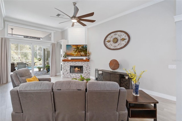 living room featuring a tiled fireplace, crown molding, ceiling fan, and light hardwood / wood-style flooring