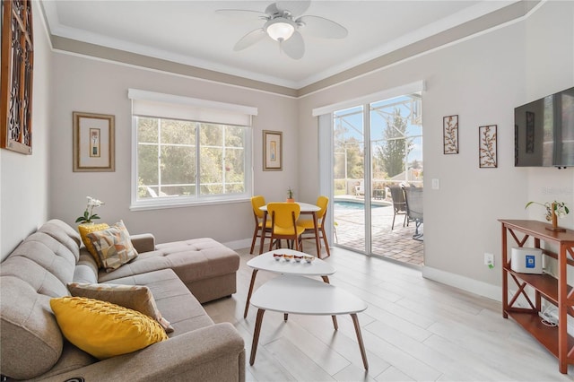 living room with a wealth of natural light, ornamental molding, light hardwood / wood-style floors, and ceiling fan