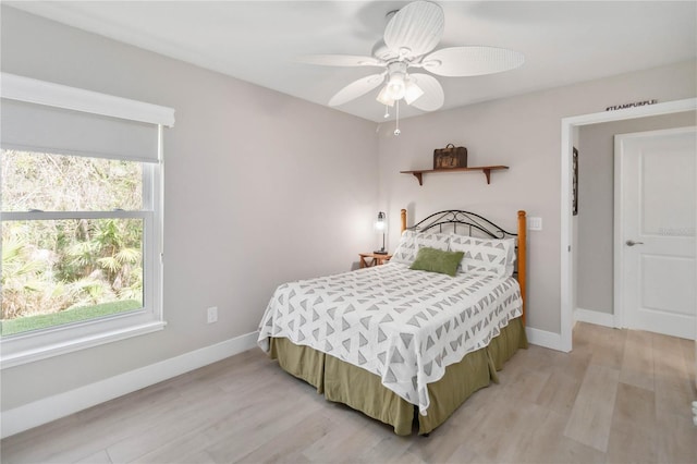 bedroom featuring ceiling fan, multiple windows, and light wood-type flooring