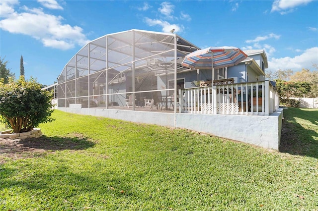 back of property featuring glass enclosure and a lawn