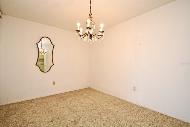 spare room featuring carpet and a notable chandelier