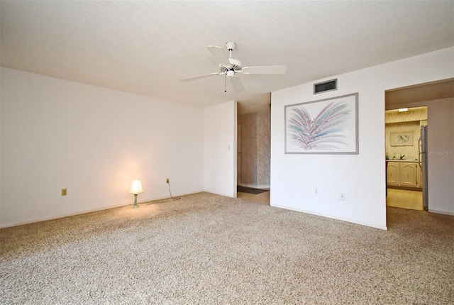 unfurnished room with ceiling fan, carpet flooring, and a textured ceiling