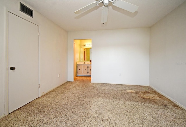 unfurnished bedroom featuring light carpet, sink, ensuite bath, and ceiling fan