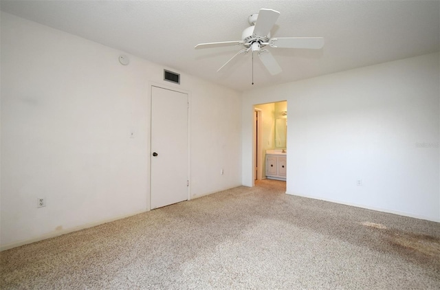 unfurnished bedroom with ensuite bathroom, ceiling fan, and carpet flooring