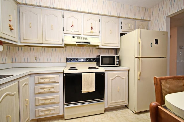 kitchen with wallpapered walls, freestanding refrigerator, under cabinet range hood, range with electric stovetop, and stainless steel microwave