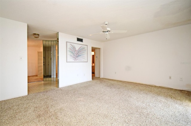 empty room featuring visible vents, ceiling fan, and carpet flooring