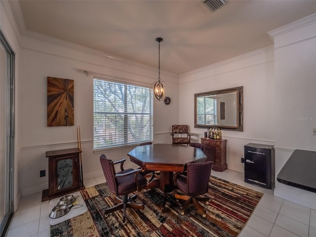 tiled dining room with ornamental molding and an inviting chandelier